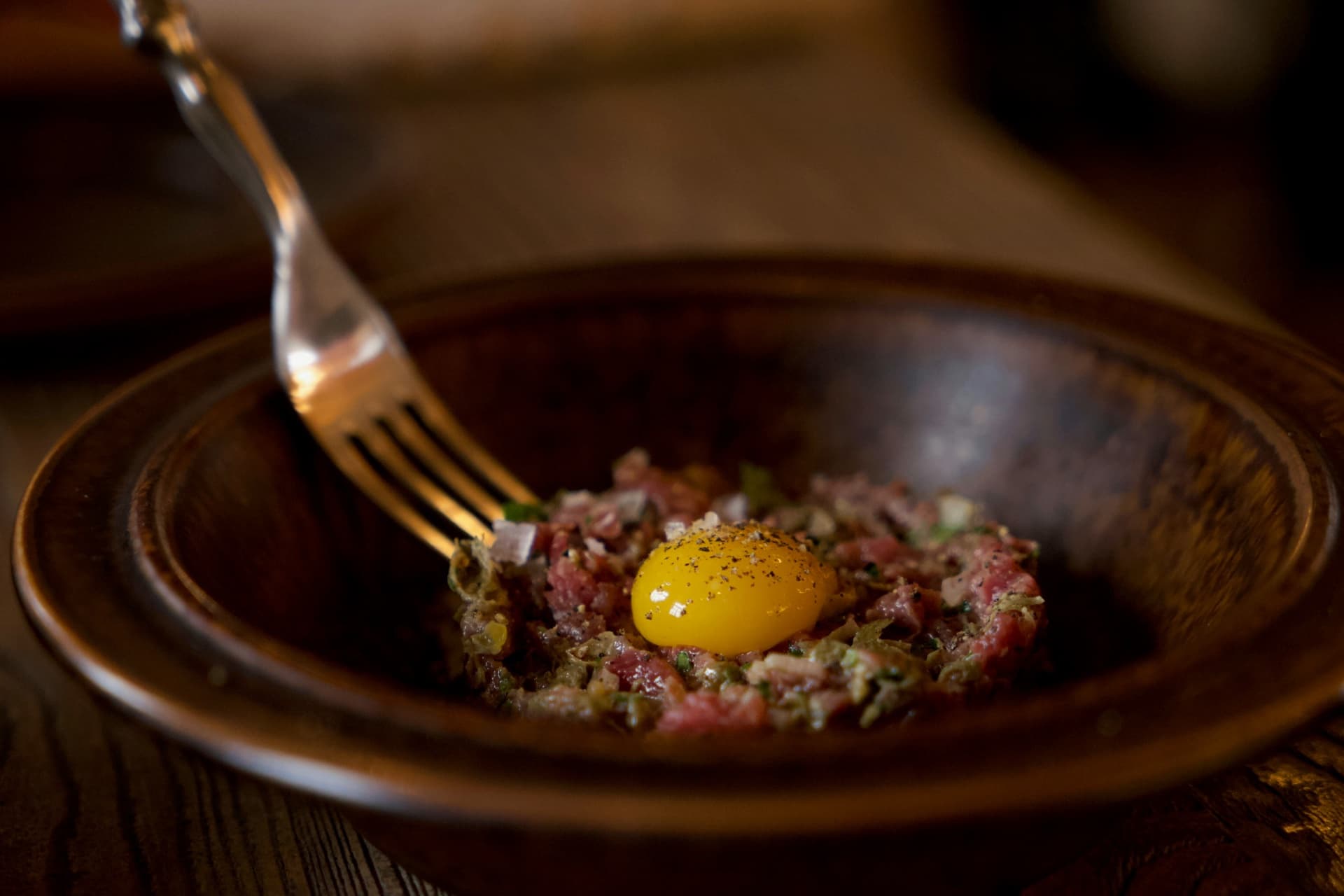 Tartare di manzo con tuorlo d'uovo in ciotola scura, Carpaccio Beef Restaurant Roma